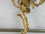 a gold candle holder on the wall next to a mirror