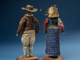 two figurines of a man and a woman wearing hats and dresses