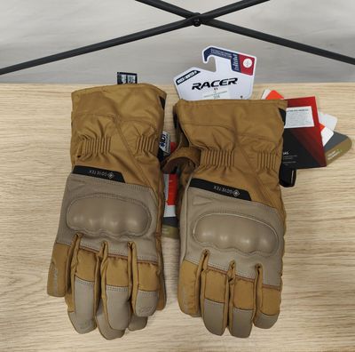 une paire de gants beiges posée sur une table en bois, avec un téléphone portable en arrière-plan