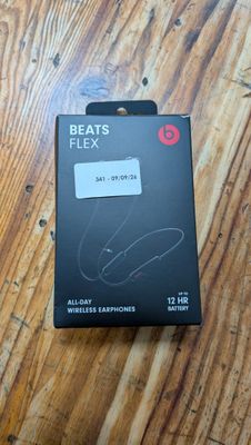 La boîte des écouteurs Beats Flexx est posée sur une table en bois.