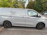 a silver van parked in a parking lot with trees in the background