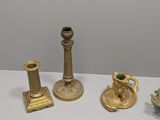 three gold candlesticks and a candle holder on a table