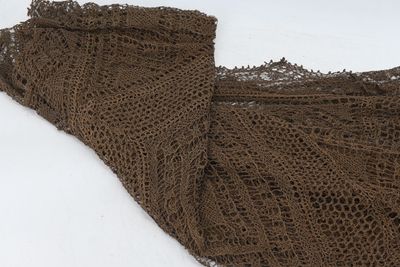 un gros plan sur un morceau de dentelle posé sur un sol recouvert de neige