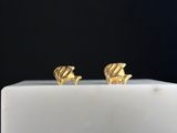 a pair of gold plated fish stud earrings on a white pedestal