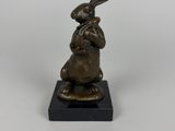 une statue en bronze représentant un lapin assis sur un socle noir