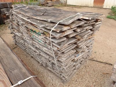 un tas de bois posé sur le sol à côté d'un bâtiment