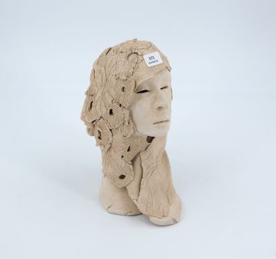 un gros plan d'une sculpture en argile représentant la tête d'une femme, posée sur une surface blanche