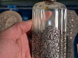 a person holding a glass bottle with silver decorations on it