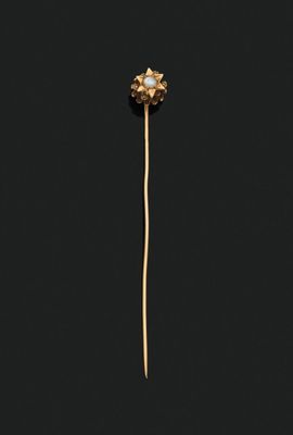 a close up of a gold and pearl broochle on a black background