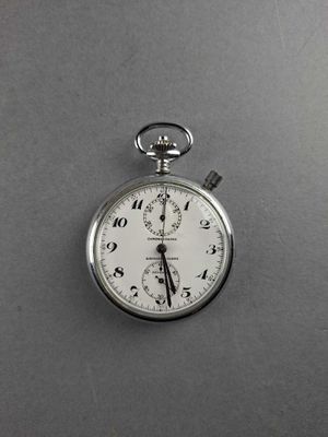 a silver pocket watch on a gray surface