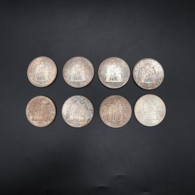 a group of six silver coins on a black surface