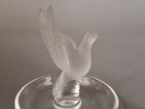 a glass bird sitting on top of a glass plate