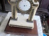 une petite horloge posée sur une table, sur laquelle est posée une note