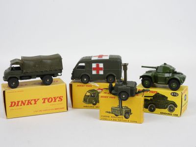 Trois véhicules militaires miniatures sont posés sur des cartons, sur une surface blanche.