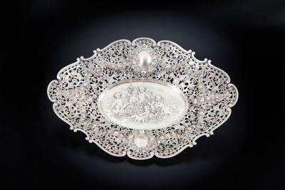 une assiette ancienne en argent sur laquelle est représenté un homme et une femme
