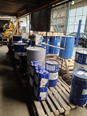 de nombreux fûts et bidons posés sur une palette dans un entrepôt