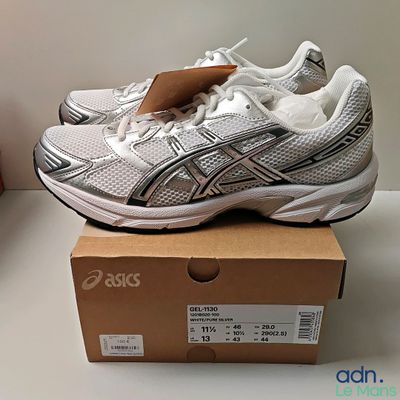 deux paires de chaussures de course Asics posées sur une boîte, elle-même posée sur une table