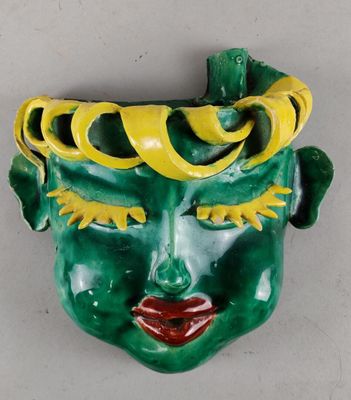 un masque vert et jaune sur un mur blanc