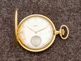une montre de poche en or posée sur une surface marron