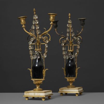 une paire de chandeliers noirs et dorés sur des socles en marbre