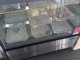 a glass display case with trays of food in it