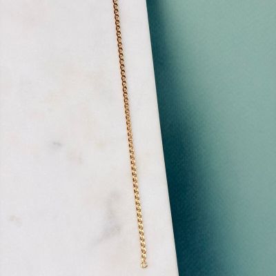 a necklace with a gold chain hanging from it on a marble slab