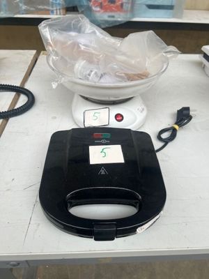 un grille-pain noir et blanc posé sur une table à côté d'un bol de nourriture