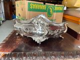 a silver sculpture on a table with a box in the background