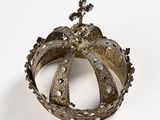 silver crown on a white surface with a cross on top