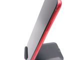 a red cell phone sitting on a stand on a white surface