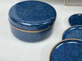 a blue container with a gold rim sitting on a table next to other items
