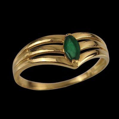 gros plan d'une bague en or avec une pierre verte