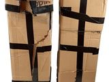pair of cardboard boxes with black tape wrapped around them on a white surface