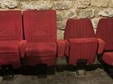 trois chaises rouges alignées les unes à côté des autres devant un mur de pierre