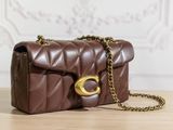 brown quilted purse with gold hardware on wooden table against white wall