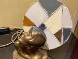 a gold statue of a man sitting on a table next to a mirror
