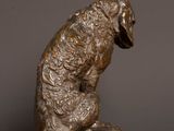 bronze statue of a dog sitting on top of a wooden table