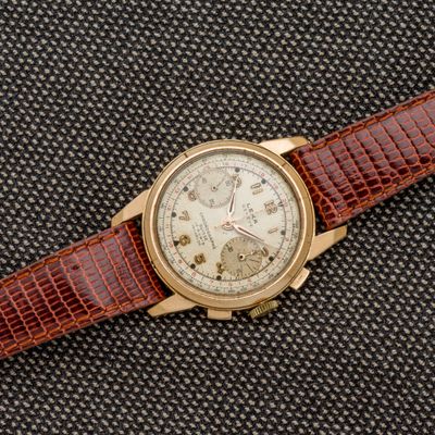 un gros plan d'une montre avec un bracelet marron sur un fond noir