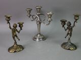 three silver candlesticks with angels on them sitting on a table