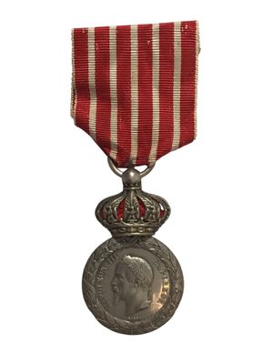 une vieille médaille ornée d'un ruban rouge et blanc sur fond blanc