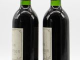 two bottles of wine sitting next to each other on a white surface