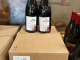 three bottles of wine sit on top of boxes in front of a painting