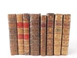 several old books are lined up in a row on a white surface