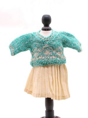 un pull et une jupe en maille présentés sur un mannequin, devant un fond blanc