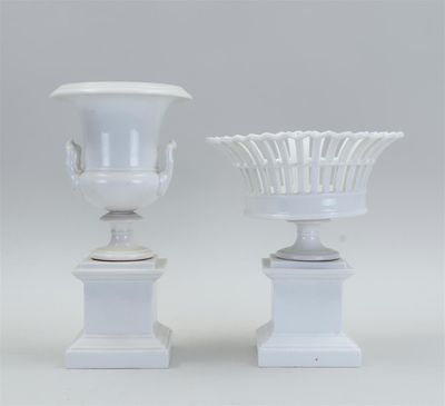 pair of white vases with handles on pedestals against a gray background