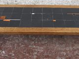 une petite table avec un plateau en carrelage noir et des pieds noirs