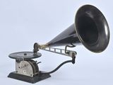 un vieux gramophone noir et argent posé sur un socle en bois