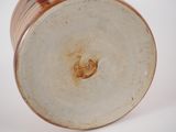 a close up of a brown vase on a white surface