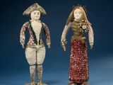 two figurines of a man and a woman standing next to each other on a blue surface