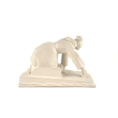 une statue représentant un homme penché en avant pour ramasser quelque chose